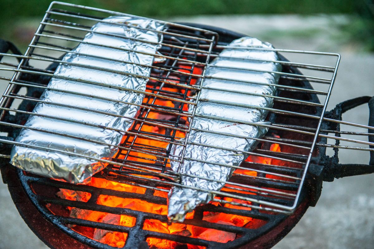 Fish fillets in aluminum foil cooking on the grill
