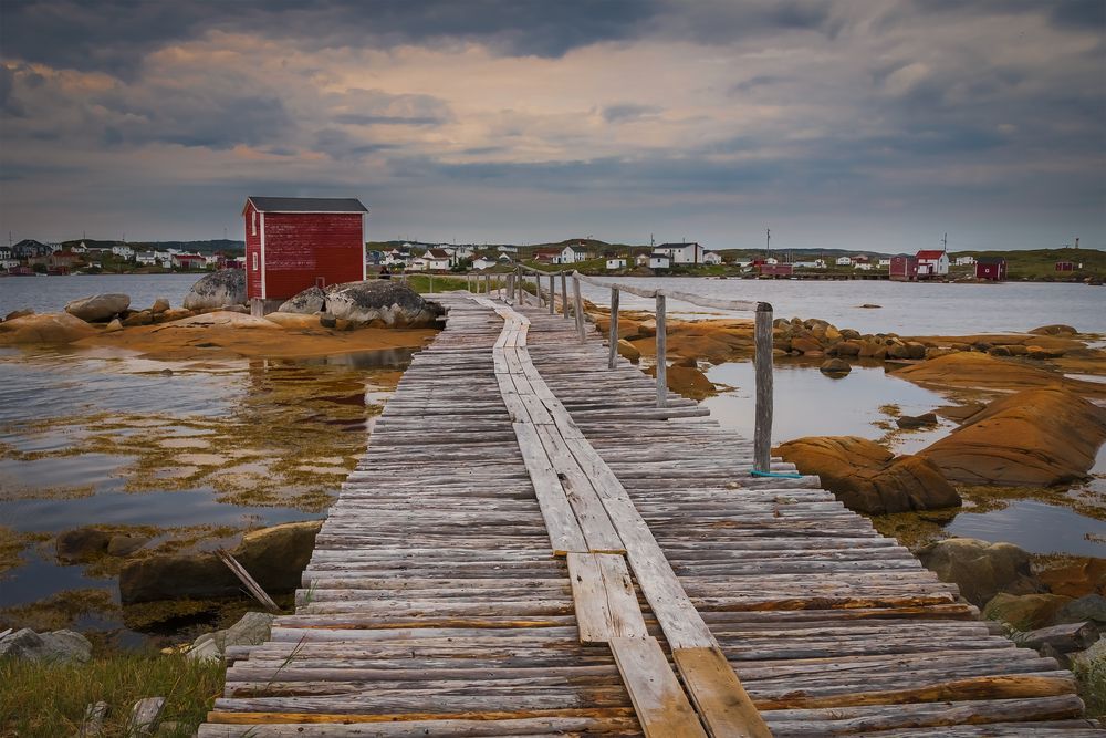 A red fishing shed at the end of a weathered wood path