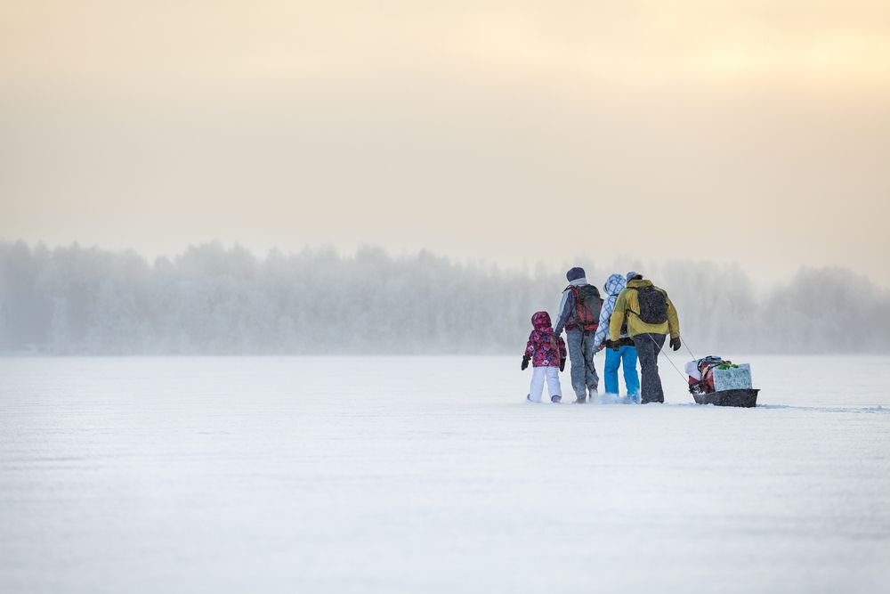 A family pulls a sled of supplies across a frozen lake
