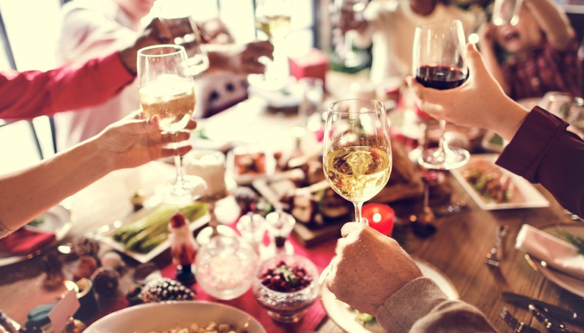A holiday dinner with wineglasses raised over the table