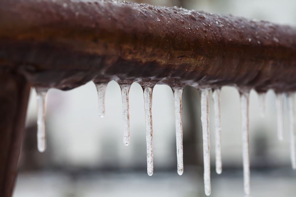 Icicles hanging from a frozen brown pipe