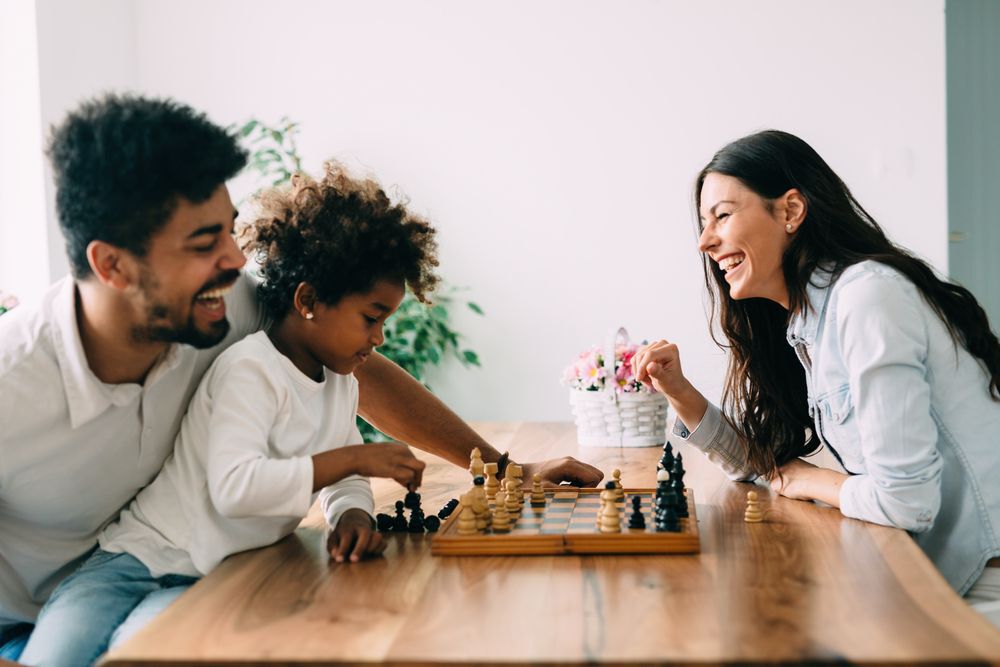 A family laughs while playing chess