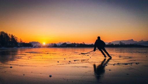 person-playing-hockey-on-ice-rink-natural-on-lake