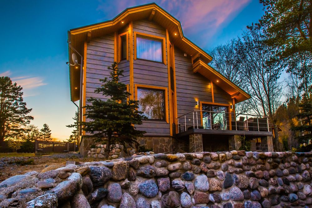 ottage decorated with natural stone. Cottage with balcony. Two-storey house. Wooden house. Living in nature. Finishing natural stone.