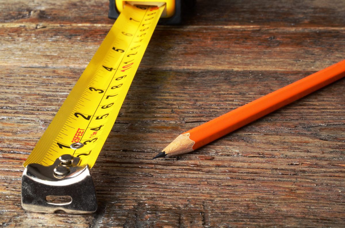 measuring tape on wooden background with red pencil