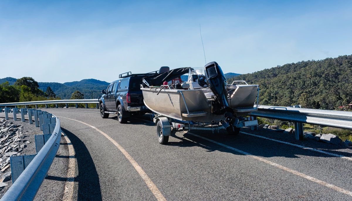Car tows a boat on a trailer on the highway