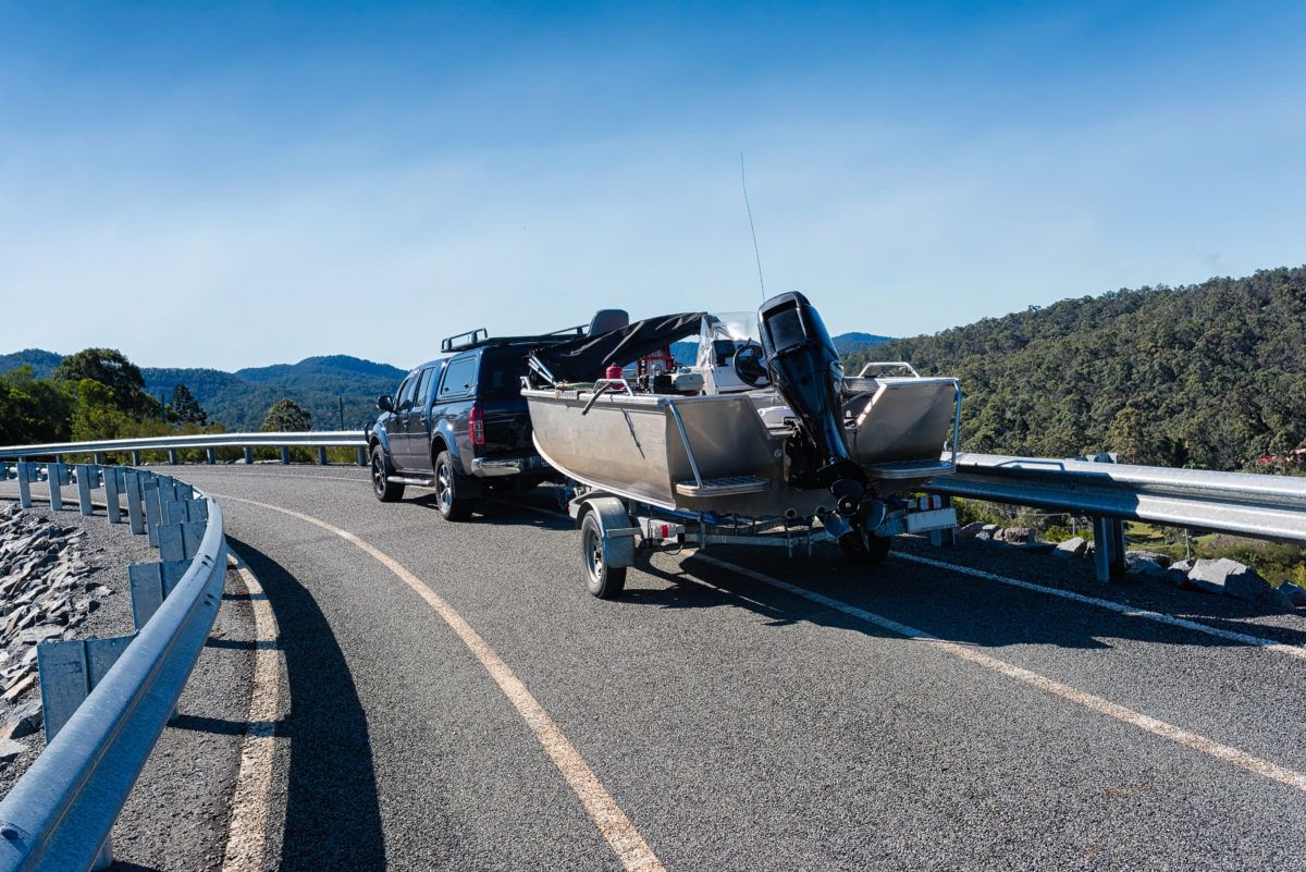 Car tows a boat on a trailer on the highway