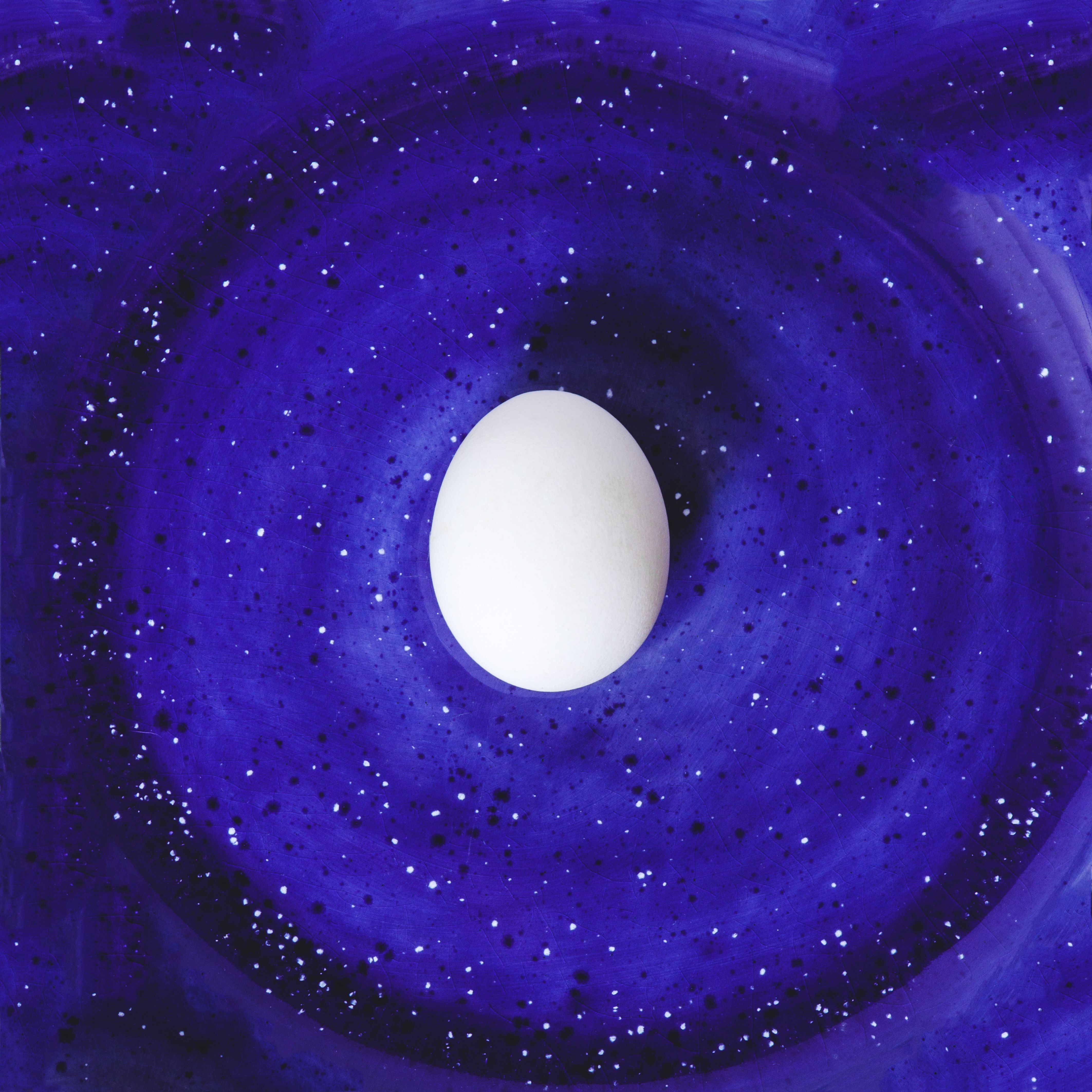 white-egg-on-abstract-painted-blue-space-background