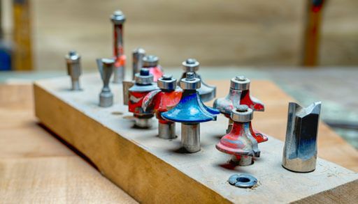side view of a selection of red and blue woodworking router bits for router machine on a wooden surface