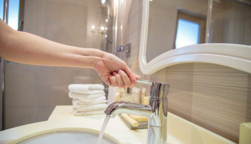 person-turning-on-bathroom-tap