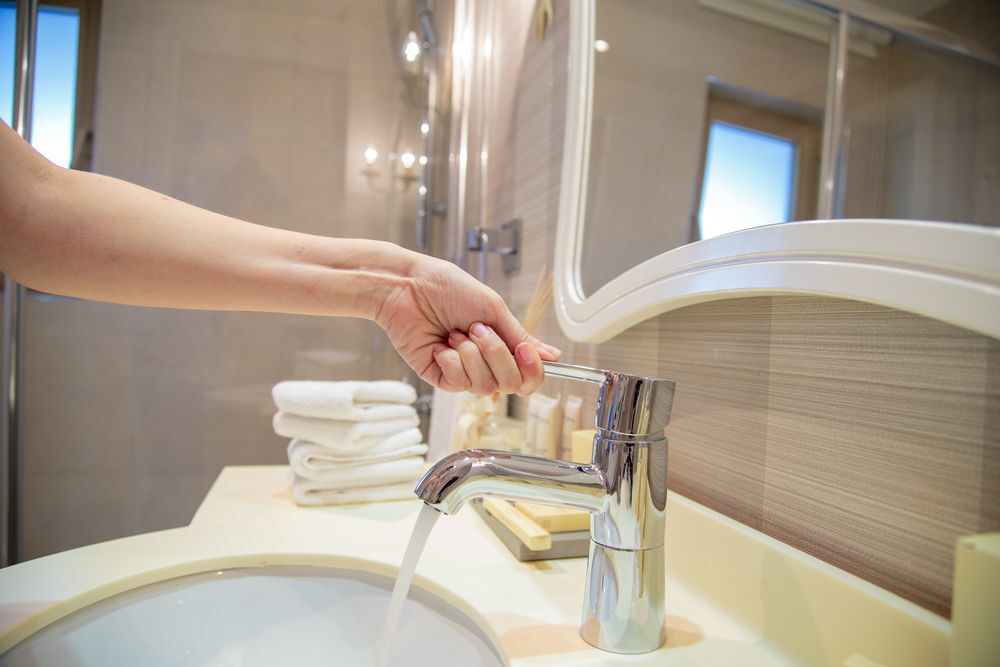 person-turning-on-bathroom-tap