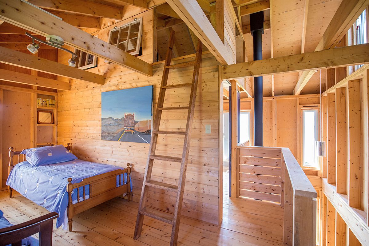 Interior view of bed, painting, and ladder leading to loft