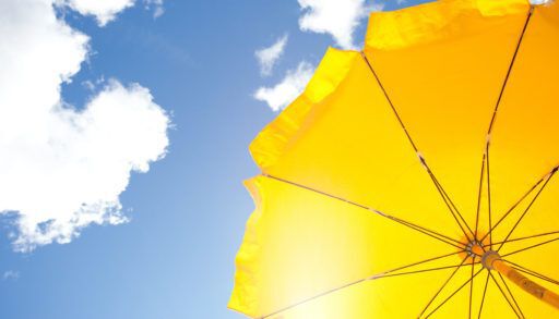 A yellow umbrella against a blue sky, blocking out bright sun