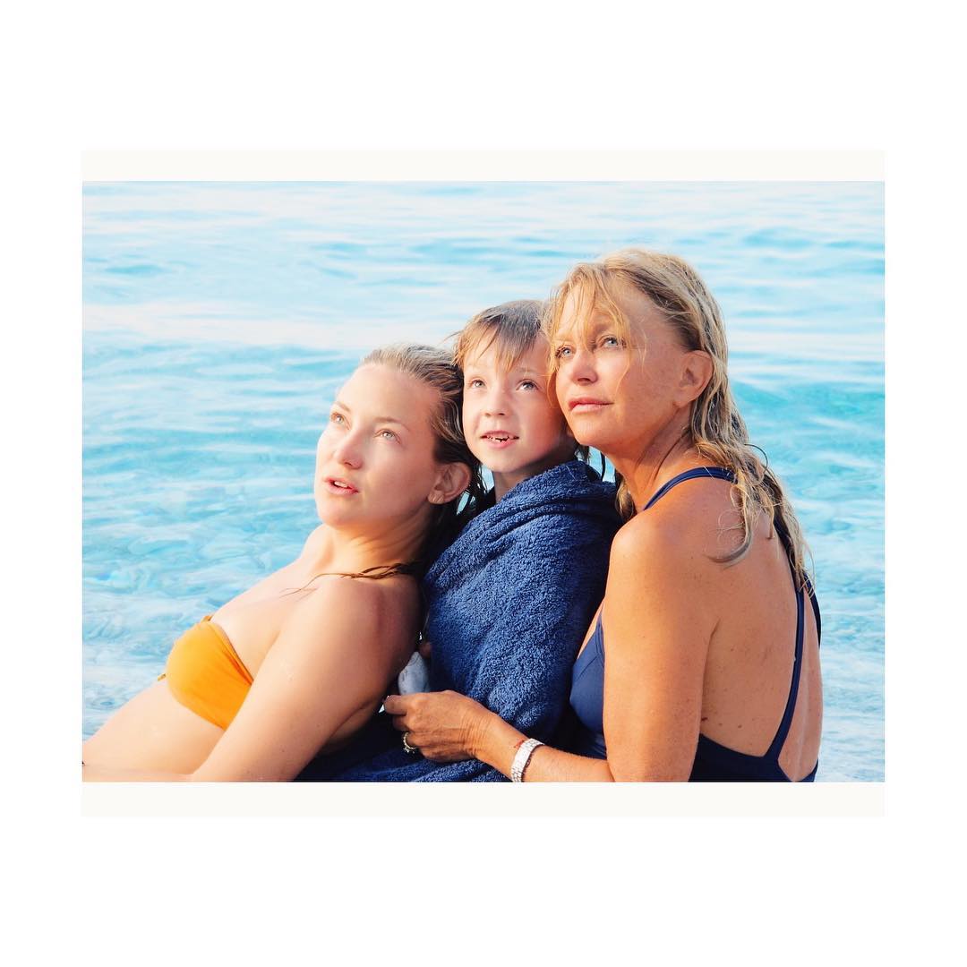 Kate Hudson, her son, and Goldie Hawn in front of a lake