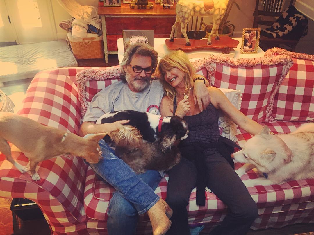 Kurt Russell and Goldie Hawn on a couch with their dogs