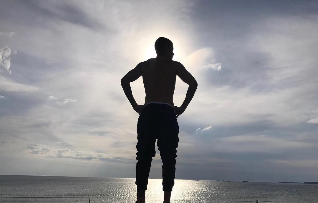 Silhouette of Justin Bieber standing by lake