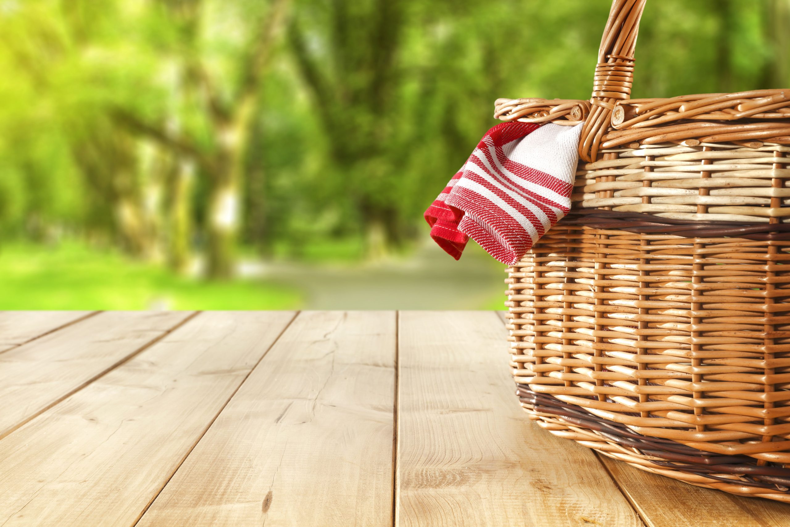 Picnic basket with red and white napkin on wood table with