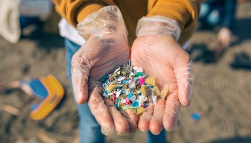 hands-holding-microplastic-particles-on-a-beach