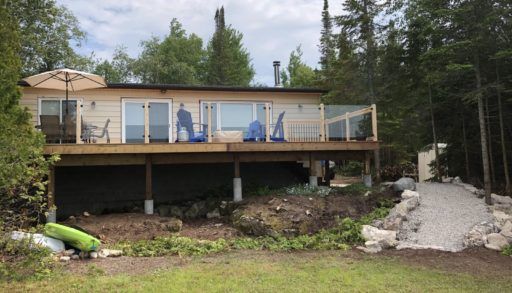 Back of single-level cottage with deck