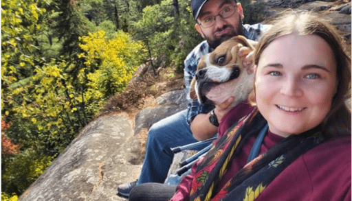 funny animal photo, dog with goofy grin next to owners on a hike