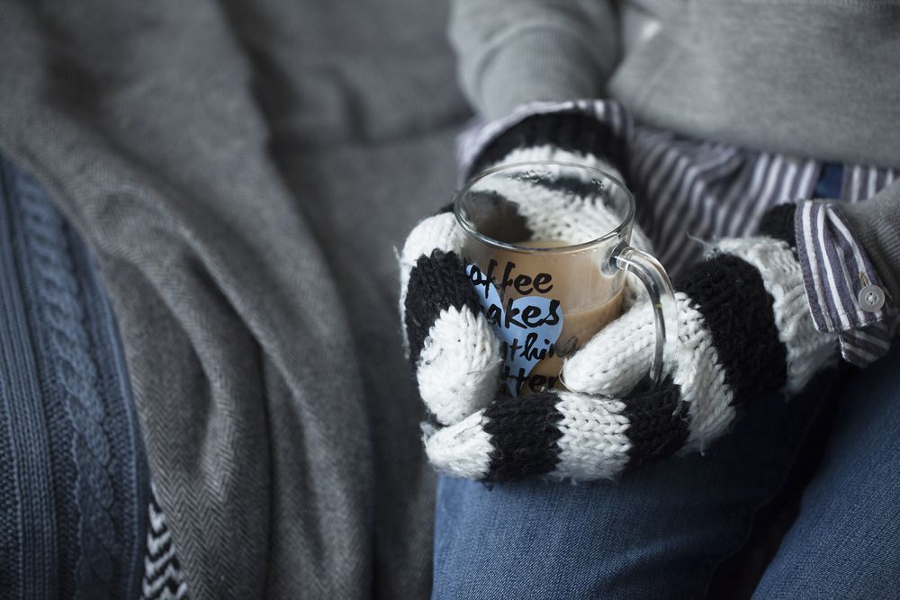 hands holding a mug with mittens on