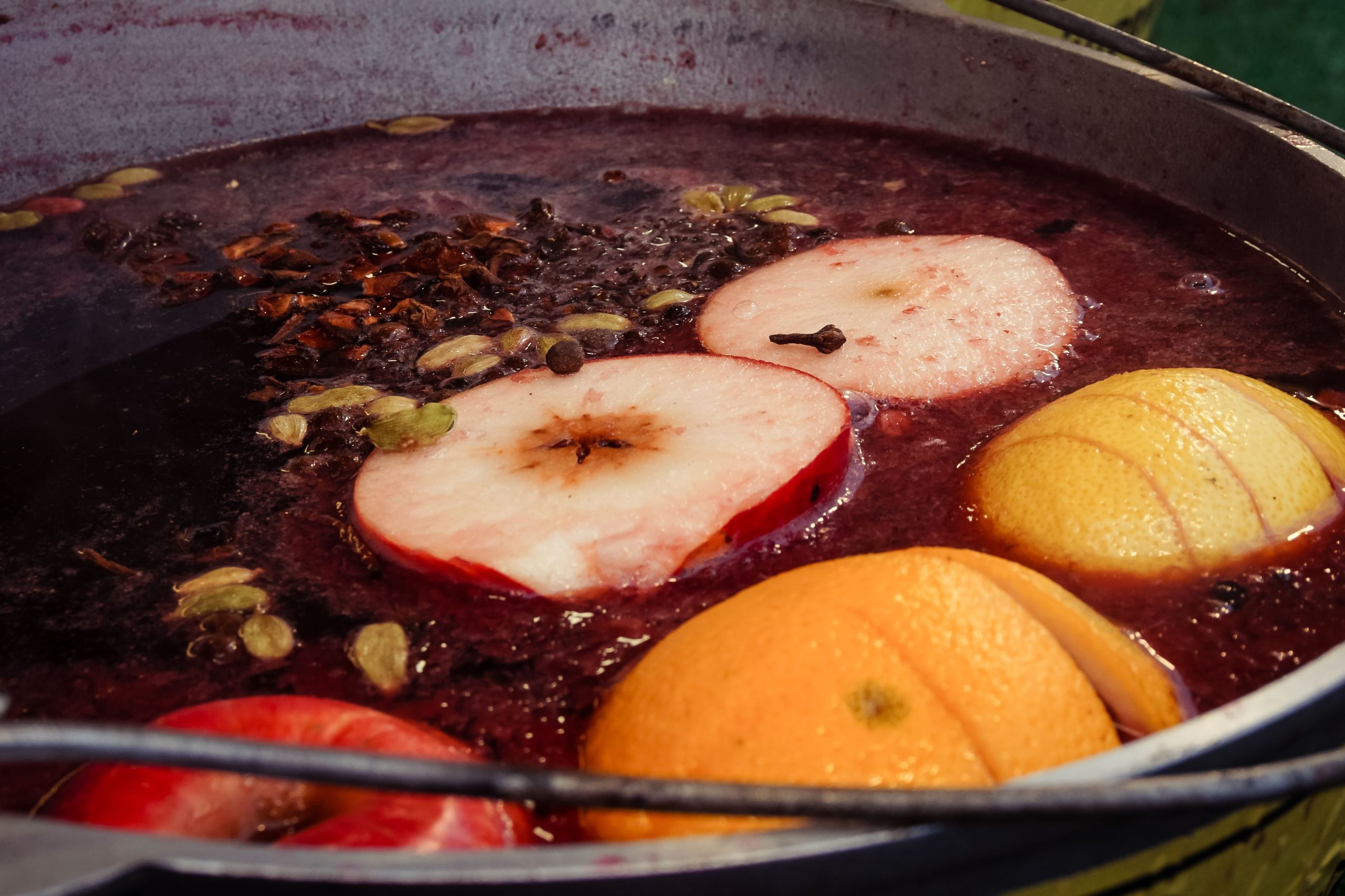 Fruit and spices float in mulled wine in a pot