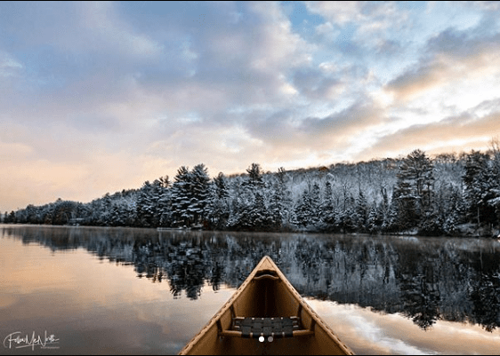 canoe on lake with snowy trees in background