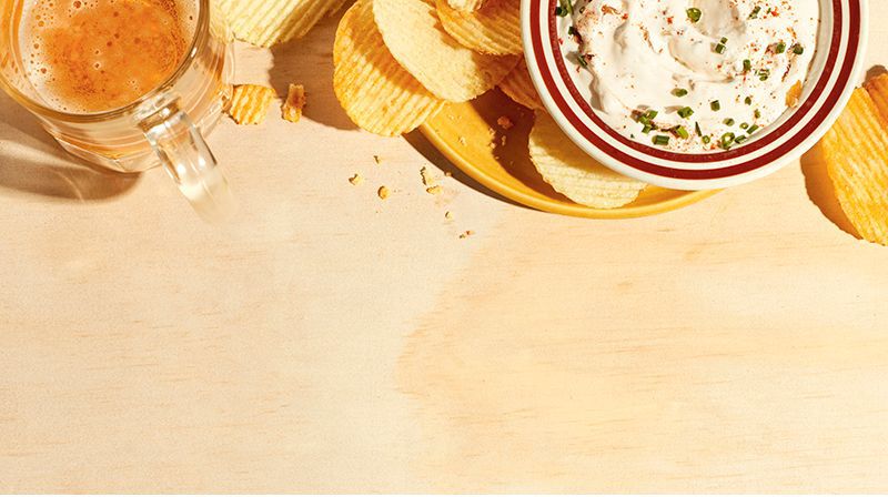 onion chip dip in a bowl with chips and beer