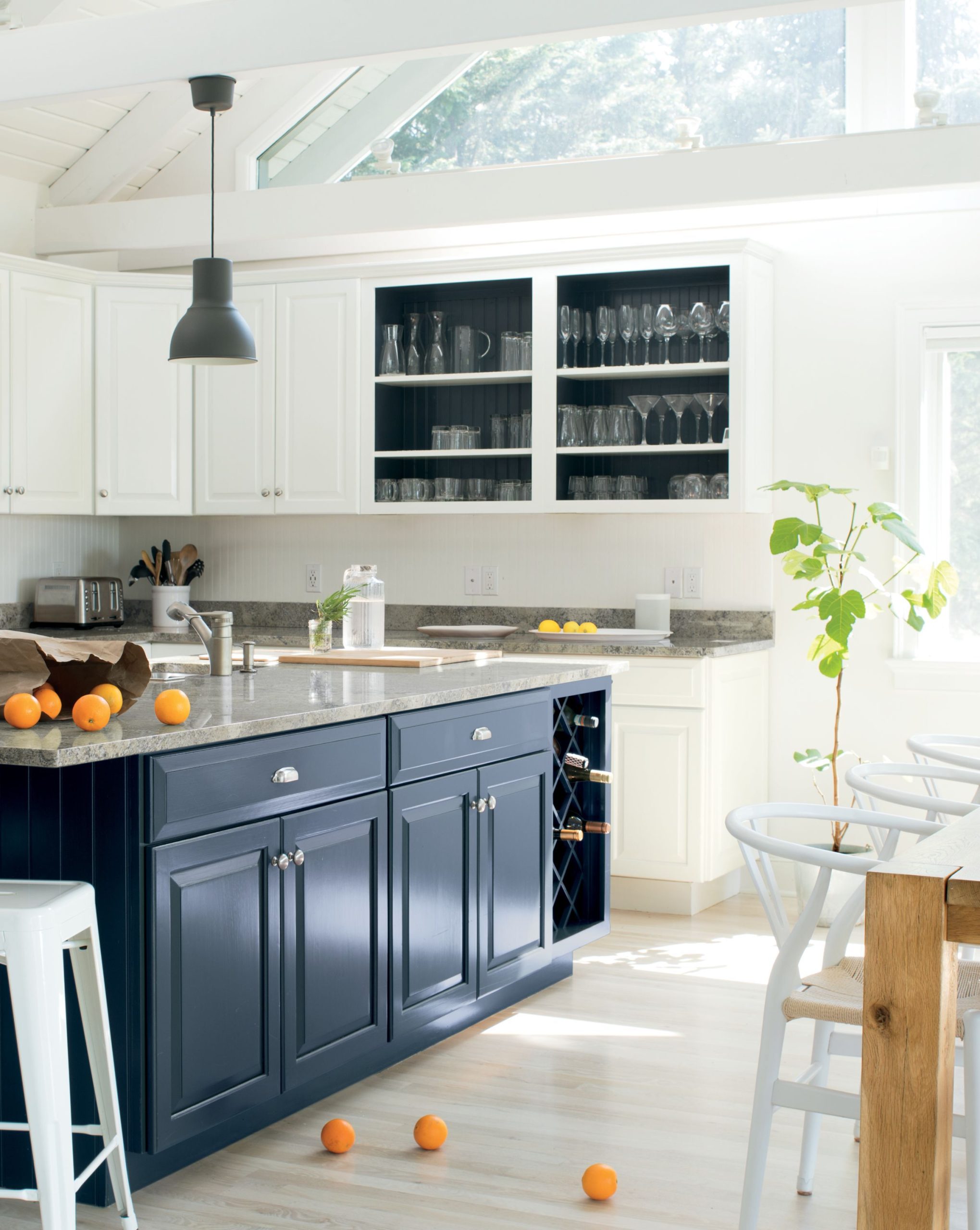 A dark grey, traditional island in a kitchen with white cabinets