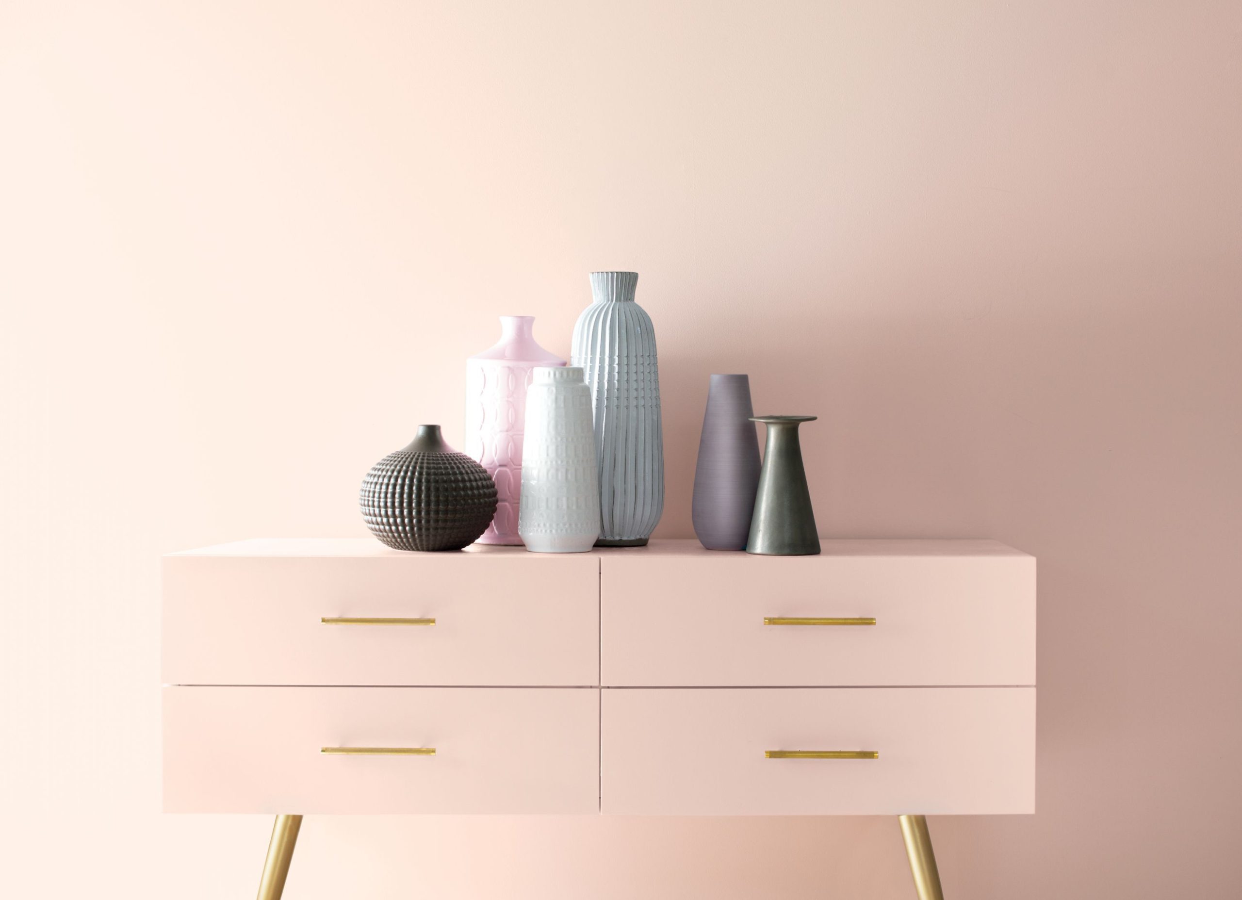 A soft pink credenza with pastel-coloured vases