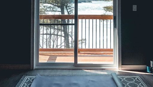 yoga mat on rug, looking through sliding door out onto a frozen lake, self isolation