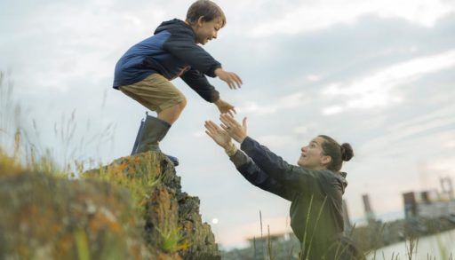 a kid jumps into his mother's arms in nature