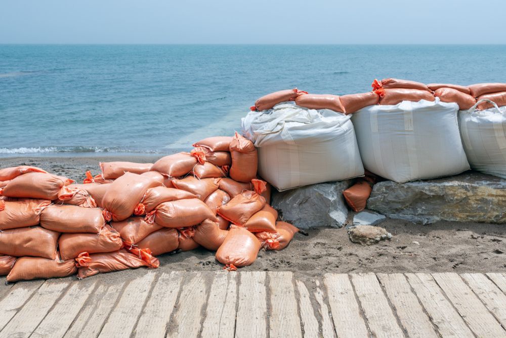 Plastic flood protection sandbags stacked into a temporary wall along lakeshore