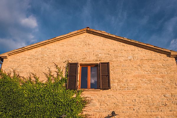An Italian stone house with an open gable roof.