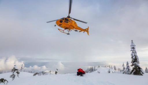 North Vancouver, British Columbia, Canada - Feb 17, 2020: North Shore Search and Rescue are rescuing a man skier with a broken leg in the backcountry of Seymour Mountain with a helicopter in winter.