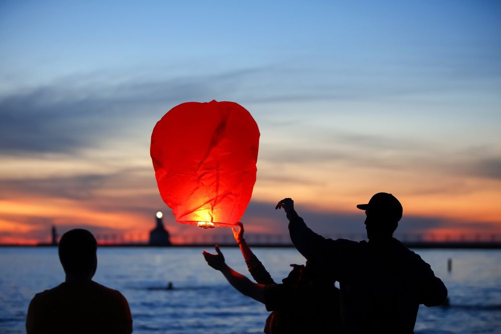 A group releasing sky lanterns by the lake