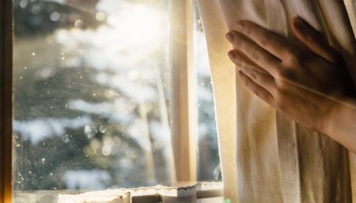 Hand Opens Curtain on the Wooden Cottage House Window to look for wildlife. Bright Sunlight Shines Through.
