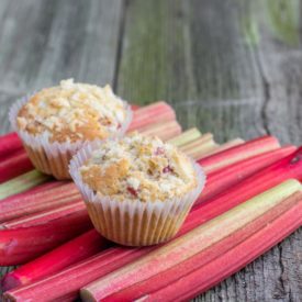 Two muffins sitting on top of a pile of rhubarb