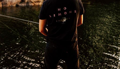 Derek Blais standing on Georgian Bay rock fishing with a black no lemons shirt