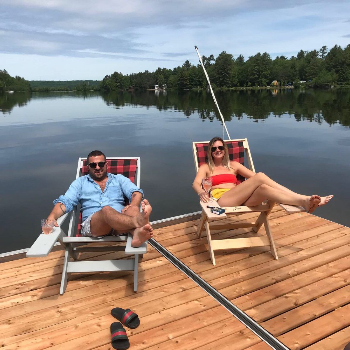 a man and a woman sitting in halihammock chairs on a dock overlooking a like