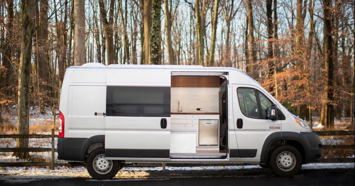 electric campervan sitting in front of a forest