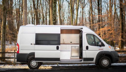 electric campervan sitting in front of a forest