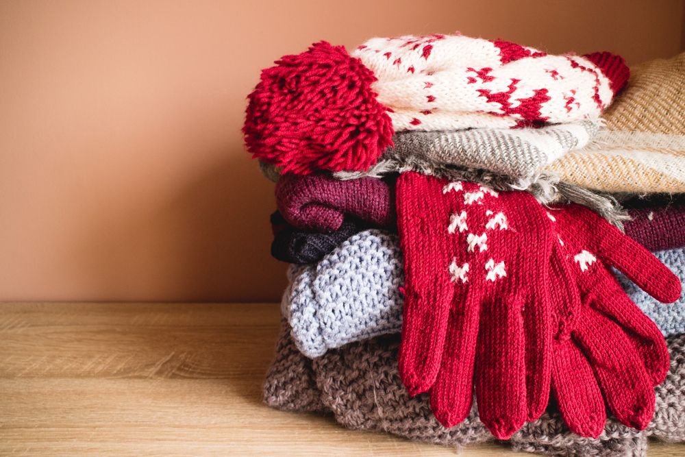 Pile of winter clothes, warm knitted clothing, hat gloves sweaters for cold weather