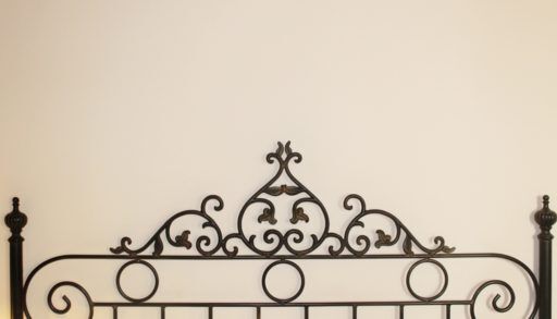 Head piece of an antique brass bed in front of a white wall