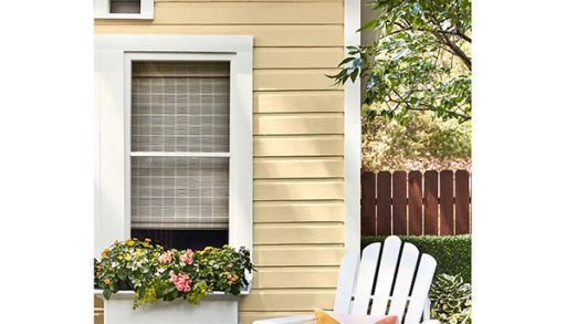 yellow paint colour on the side of a small house or cabin with a white adirondack chair in front