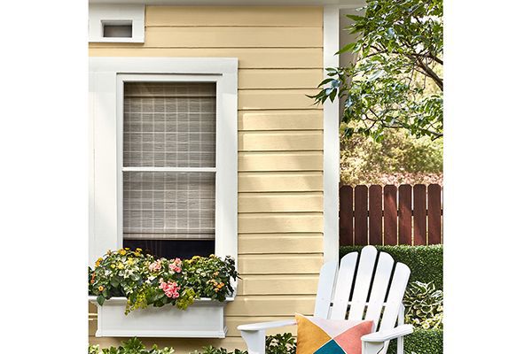 yellow paint colour on the side of a small house or cabin with a white adirondack chair in front