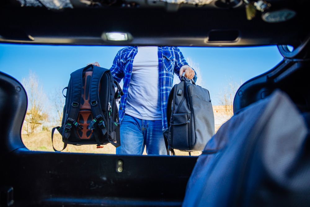 A man loading bags into the trunk of his car
