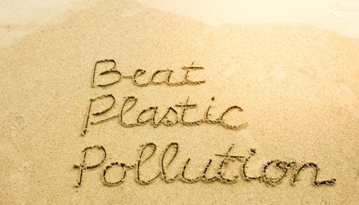 The words "Beat Plastic Pollution" written in the sand