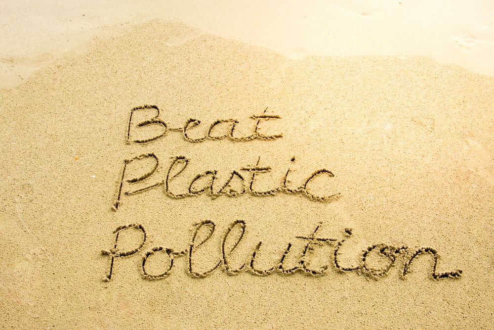 The words "Beat Plastic Pollution" written in the sand
