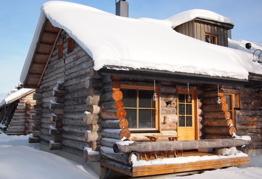 A snow-covered cabin against a blue sky background